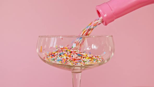 Colorful Candy Confectionery Run Poured Into a Wineglass Glass on Pink Background