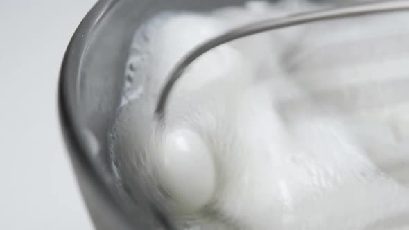 Stirring and whipping milk with a mixer in a gray bowl