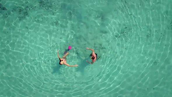 Aerial view of man and woman with masks and flippers swimming on their backs.