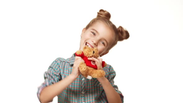 Young Adorable Caucasian Kid Girl with Two Hair Buns Showing Small Teddy Bear Smiling Jumping on