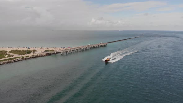 Aerial View of Boat Driving by Beach Pier in Ocean