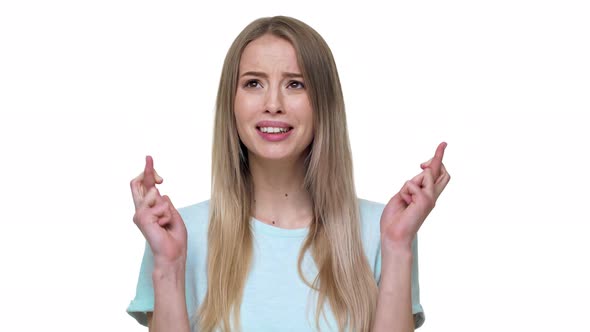 Portrait of Woman Keeping Fingers Crossed in Praying Pose and Saying God Please Isolated Over White