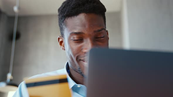 Smiling young man using laptop enter credit card numbers