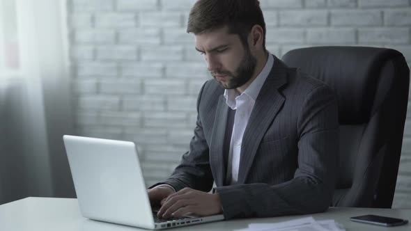 Businessman Responding to Email on Laptop, Pondering Over Forthcoming Deal