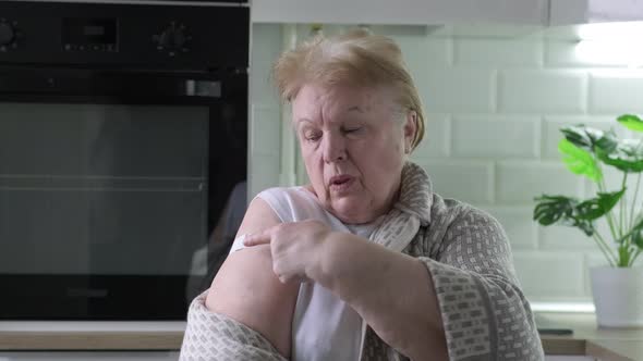 Smiling Senior Woman Showing Bandage on Arm After Covid Vaccination