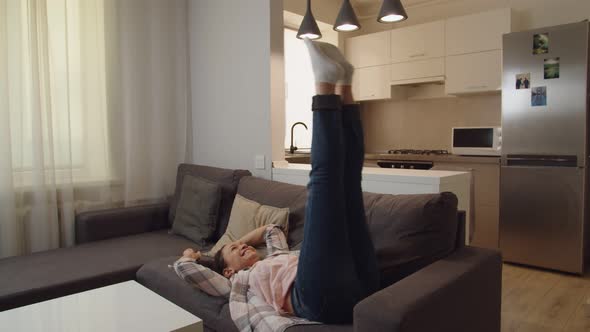 Happy Adult Woman Jumping Over on Sofa Expressing Positive Emotions