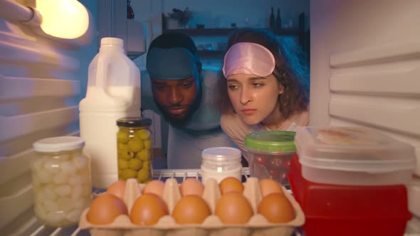 Happy Couple Take Food From Refrigerator in Kitchen at Night