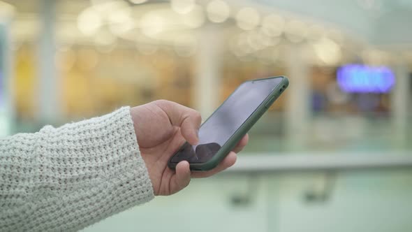 Handheld Shot of Male Hand Scrolling a Phone on Blurred Yellow Background