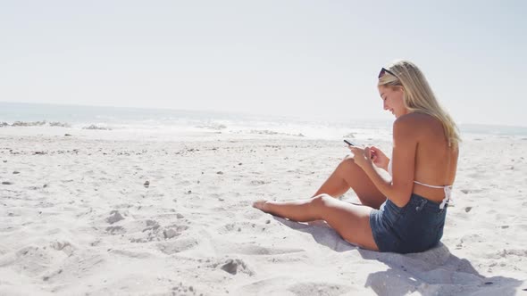 Caucasian woman using her smartphone on the beach