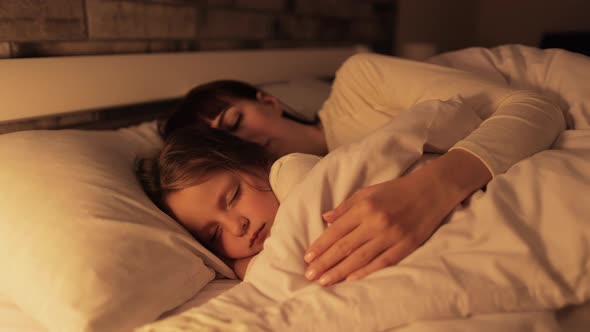 Young Mother and Little Daughter Sleeping in Bed Together