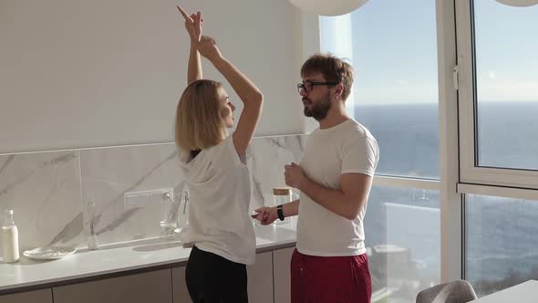 Young Caucasian Couple Wearing Pyjamas Funnily Dancing and Singing Early in Morning Preparing for