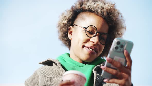 Handsome adult African woman wearing casual clothes looking at phone