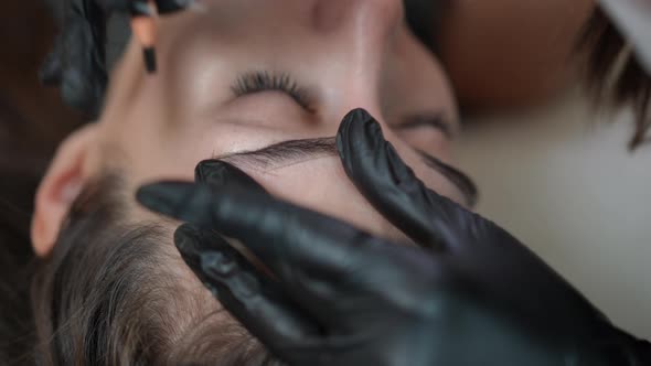 Closeup Beautician Hand in Glove Shaping Eyebrow for Permanent Makeup