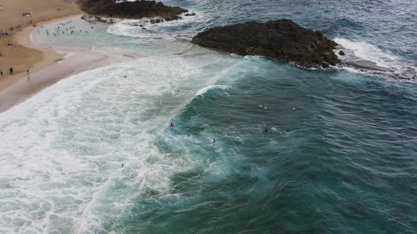 People Swim And Surf At La Poza del Obispo Beach With Large Waves In Arecibo, Puerto Rico. - aerial