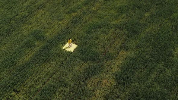 Aerial Photography. A Dancer in Yellow Clothes Is Dancing in the Middle of a Green Grass Field