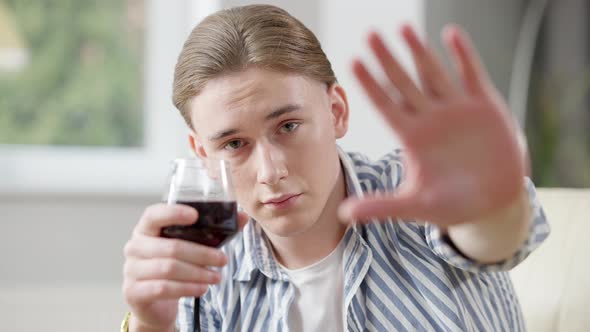 Young Caucasian Handsome Man Stretching Palm Looking at Camera and Holding Glass with Red Wine