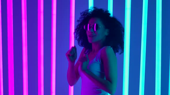 Young African American Woman in Stylish Sunglasses Dancing in the Studio Against a Background of