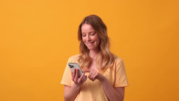 Happy blonde woman wearing yellow t-shirt typing by phone