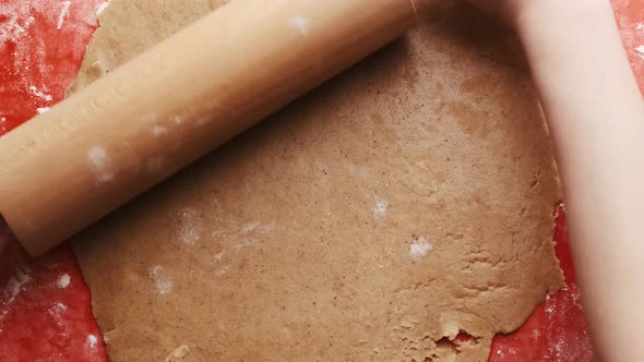 Woman Rolling Out the Dough with a Rolling Pin on a Red Silicone Baking Mat for Gingerbread Cookies