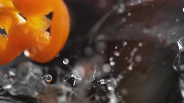Throwing sliced orange bell pepper into water. Slow Motion.