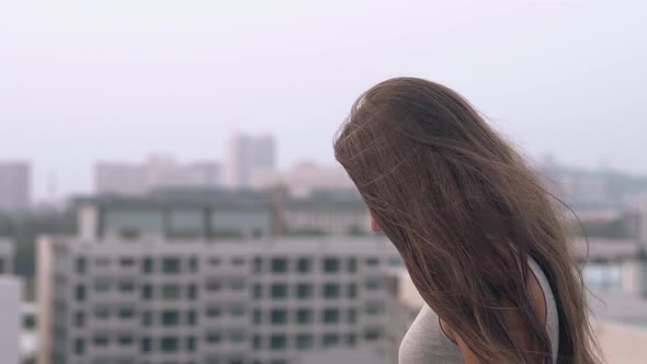 Wind Blows on Beautiful Woman Sitting Against Blurry Hotels