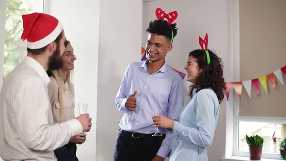 Multiethnic Group of Happy Office Workers Holding Glasses with Sparkling Wine and Talking During