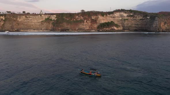 Tourists in motorized traditional Balinese boat jukung sailing near the cliffs. Uluwatu, Bali, Indon