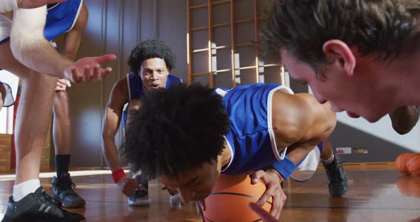 Diverse male basketball team wearing blue sportswear and doing push ups