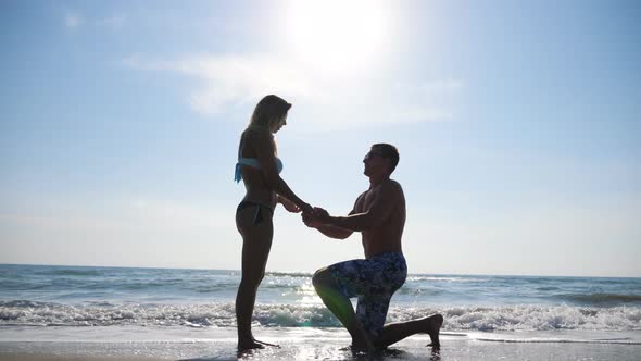 Young Man Stand on Knee and Marriage Proposal To His Girlfriend Summer Vacation. Happy Pair Hugging