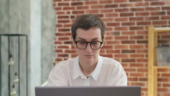 Tired Businesswoman in Glasses and a White Shirt Warms Up with Fingers Temples Working Behind a