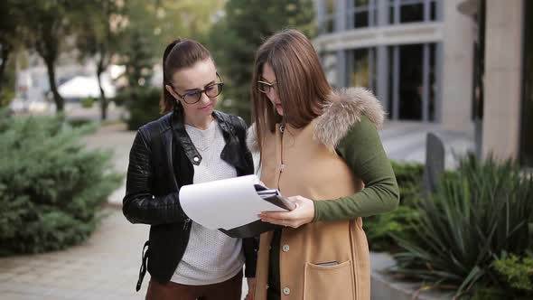 Woman Woman Realtor and Client to Discuss the Documents on the Background of the Rental Building