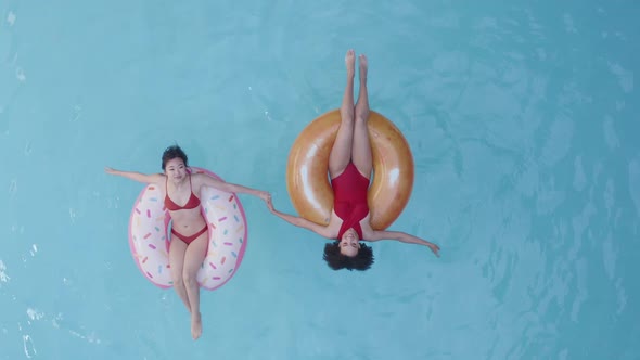 Two People Asian and Afro American Women in Red Swimsuit Relaxing Refreshing Resting in Inflatable