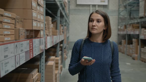 Woman with a Phone Looking for a Product in a Warehouse Store