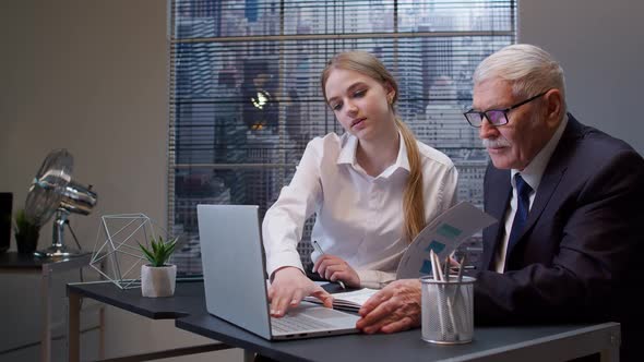 Woman Secretary Talking on Mobile Cell Phone Senior Business Man Boss Working on Laptop in Office