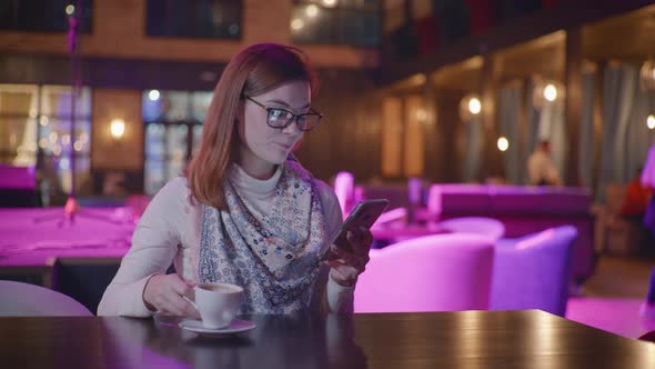 Portrait of Beautiful Smiling Girl with Glasses Using Smartphone Chatting with Friends on Social