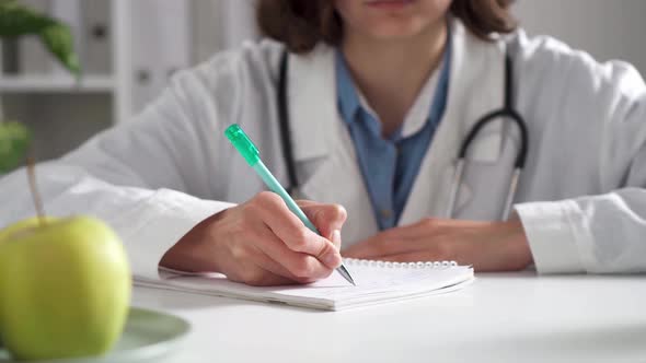 Woman Doctor Writing At Her Desk. Woman, Surgeon, Nurse, Pharmacy With Stethoscope In Hospital