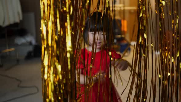 Korean Girl Child in Red Dress is Playing on Christmas Night with Golden Tinsel