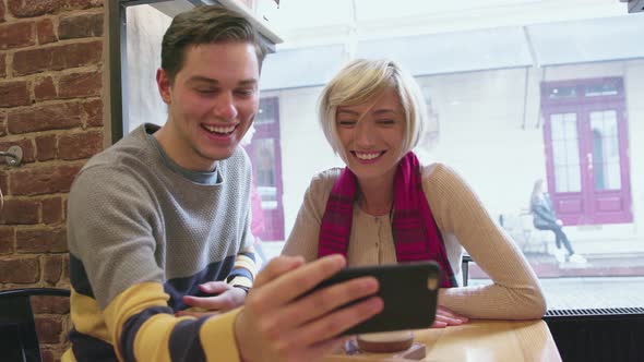 Video call. Happy couple in cafe using phone for video chat