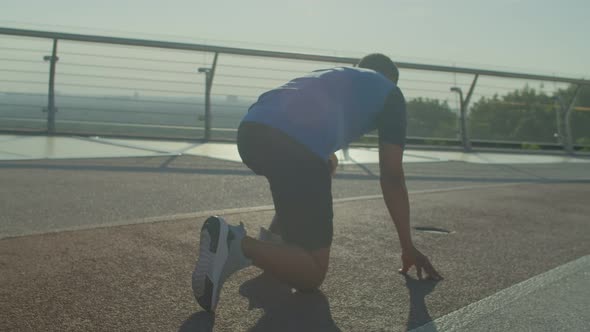 Back View of Motivated Sporty Black Athlete Ready for Run on Track at Sunrise