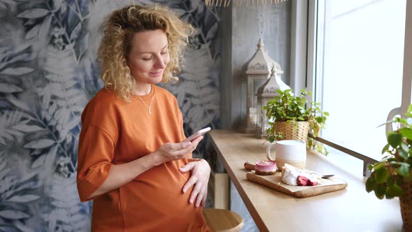 Beautiful Pregnant Woman Using Mobile Phone In Cafe