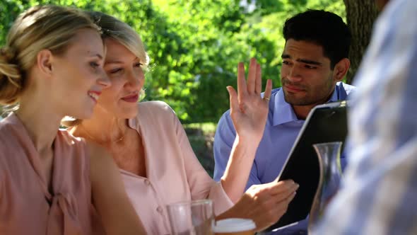 Friends discussing over clipboard at restaurant