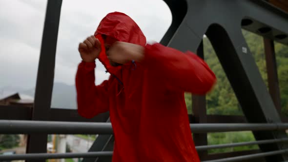 Strong Man in Red Raincoat is Training Arm Punches Outdoors in Rain Force and Strength