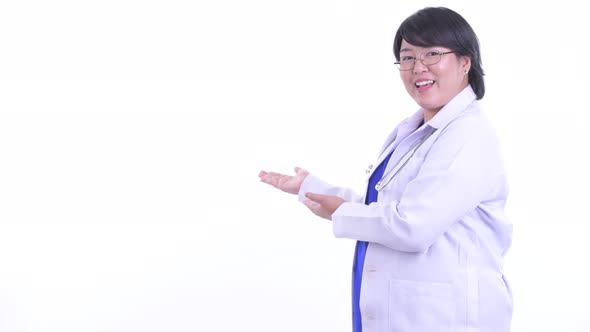 Happy Overweight Asian Woman Doctor Talking While Showing To the Back