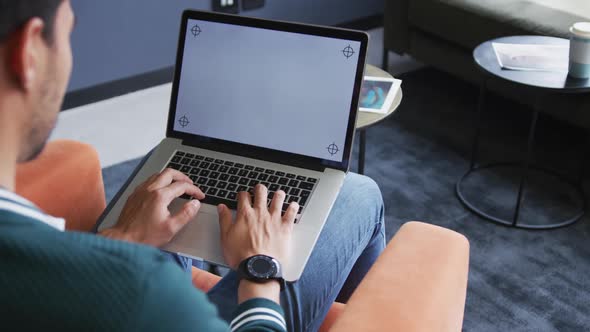 Mixed race businessman sitting using a laptop in a modern office