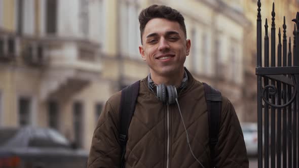 Portrait of Young Optimistic Man 20s Wearing Jacket Standing on City Street with Positive Emotions