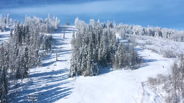 Aerial View of Ski Resort with People Skiing and Snowboarding Down the Hill