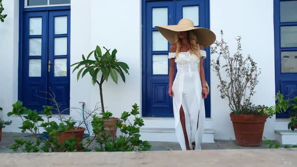 Woman in Sun Straw Hat on Background of White Building and Beautiful Blue Doors at Spetses