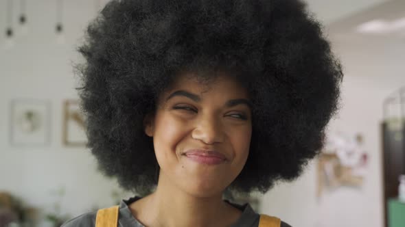 Happy African Lady with Afro Hair Looks at Camera Stands in Cafe Headshot