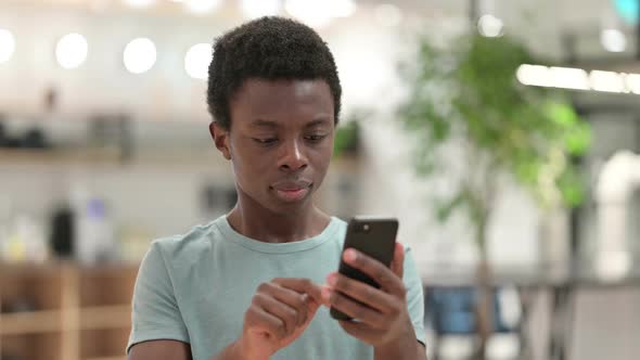 Young African Man Celebrating Success on Smartphone