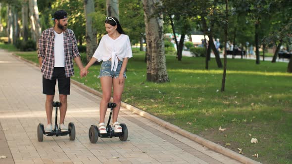 Couple Riding Hoverboards and Holding Hands